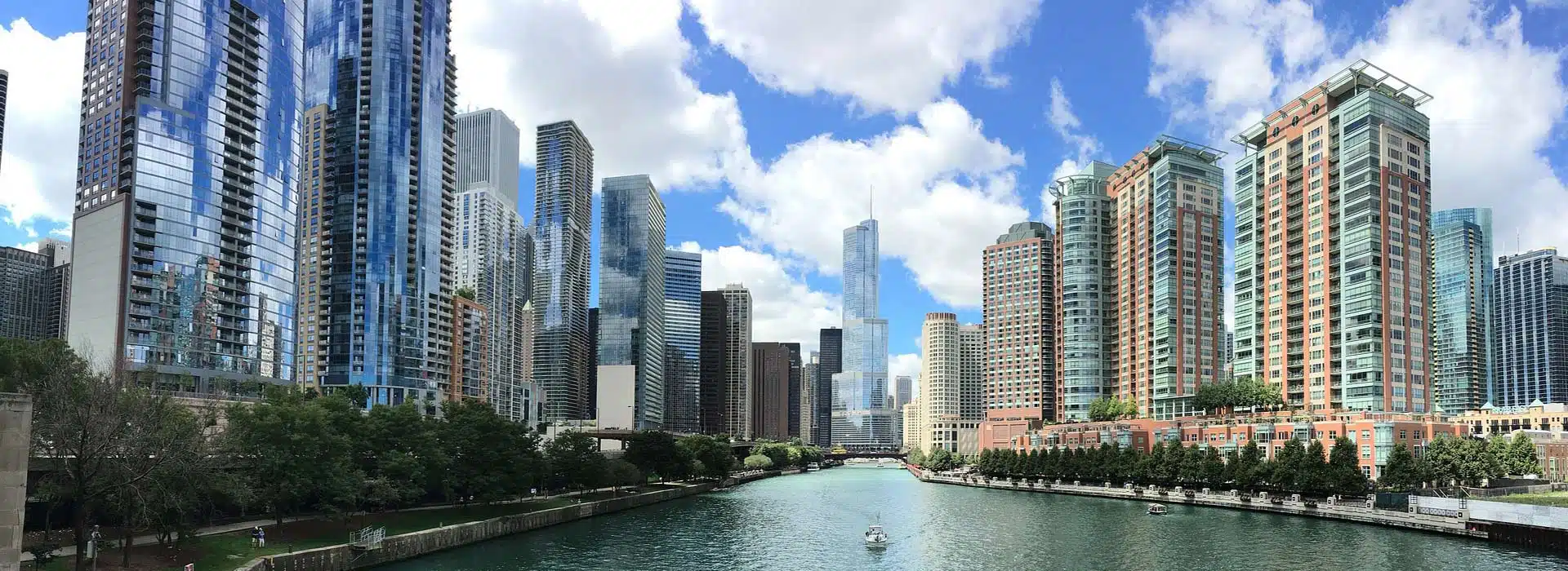 View of skyscrapers of elgin injury lawyers on both sides of a river as a boat goes down it.