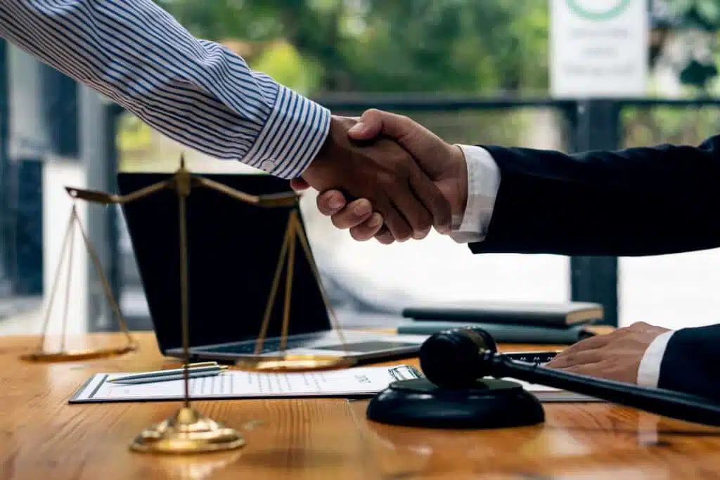Two men shaking hands with Chicago personal injury lawyers with scales of justice near.