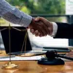 Two men shaking hands with Chicago personal injury lawyers with scales of justice near.