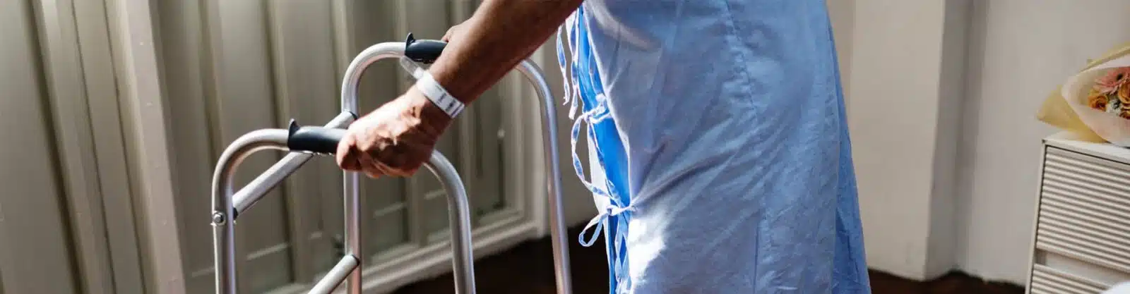 man in hospital gown using walker.