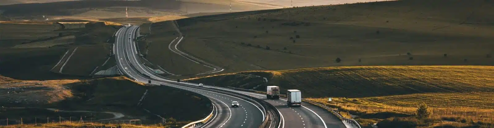 Zoomed out view of highway with rolling hills in background.