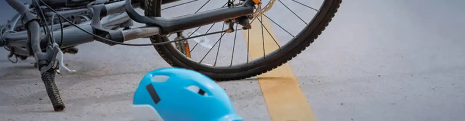 A cyclist helmet on ground by wrecked bike.