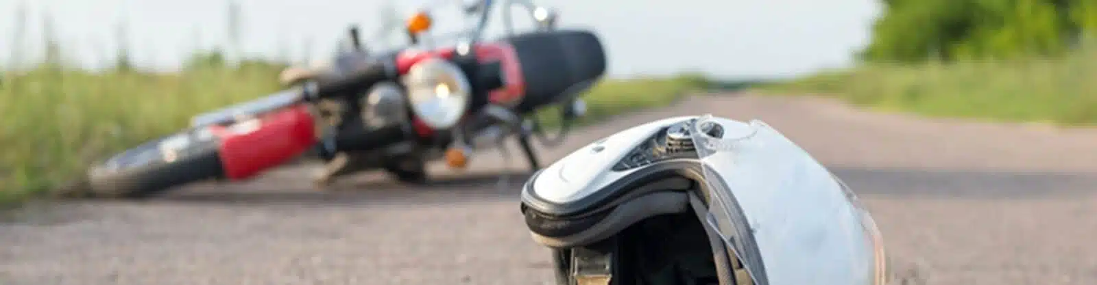 A motorcyclist helmet on ground by wrecked bike.