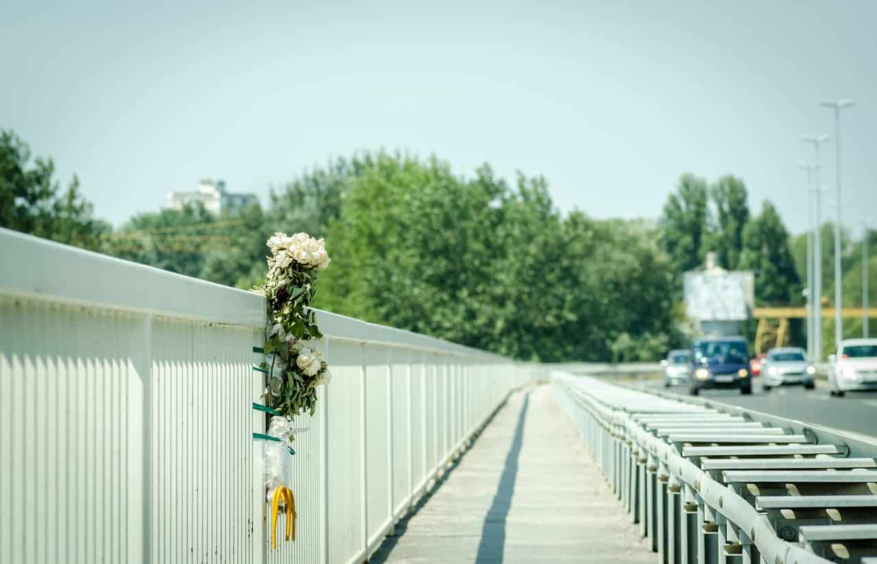 A wreath of flowers on the side of a bridge marking a death in a vehicle accident requires a wrongful death lawyer to get closure.
