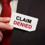 Businessman putting a card with text Claim Denied in the pocket