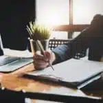 Woman holding pen reviewing contract at her desk.