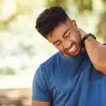Young man grabbing neck in pain from a sports injury.